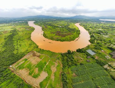 Bulutlu bir günde, tarlalar ve ağaçlarla çevrili at nalı şeklinde bir nehrin havadan çekilmiş görüntüsü.