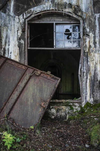 A vertical shot of an abandoned broken bunker building with mold