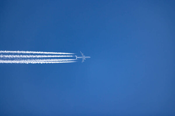 Самолет и его белый след в ясном голубом небе