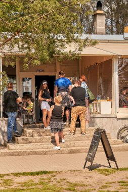 Poznan, Polonya 'da güneşli bir bahar gününde bir restoranın önünde bekleyen bir grup insan.