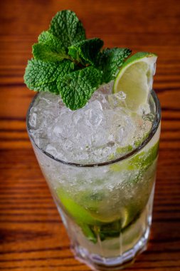 Limon dilimleri, buz ve nane yapraklı ferahlatıcı bir kokteylin dikey çekimi.