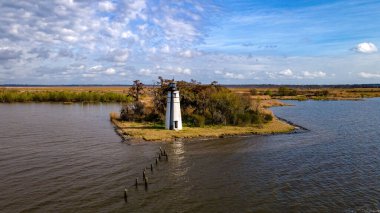Bulutlu gökyüzüne karşı beyaz bir deniz fenerinin havadan görünüşü