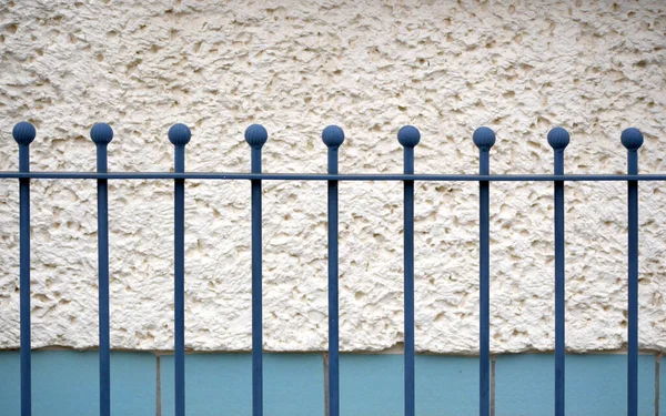blue metallic fence in front of a white house wall