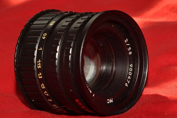 红色面料背景上的老式手工相机镜头特写 — 图库照片
