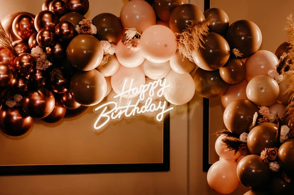 A birthday party decoration with colorful balloons and a light sign