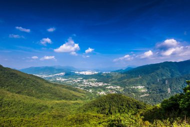 Dağ sıralarının güzel manzarası ve altında bulutlu gökyüzü olan bir kasaba.