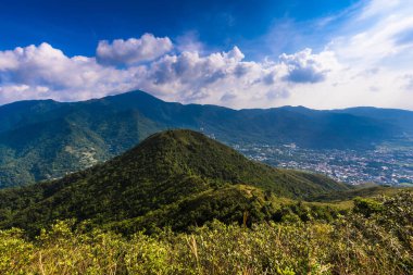 Dağ sıralarının güzel manzarası ve altında bulutlu gökyüzü olan bir kasaba.