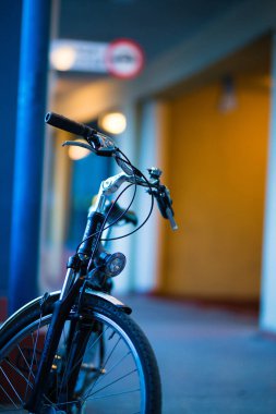 A vertical shot of a bicycle parked in a corridor inside building with blurred background