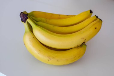 A closeup of bunch of bananas on a white surface