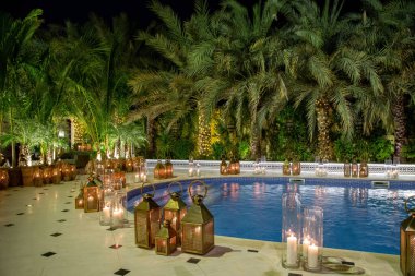 Palmiye ağaçlarının fenerleri mumlar ve gece havuzu.