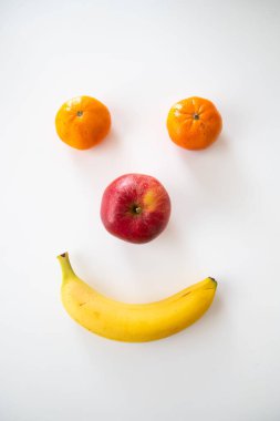 A vertical shot of a happy smiley face made out of fruits