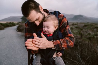 An American father and his cute little daughter in a baby carrier during a hike