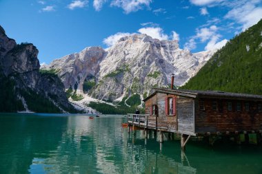 İtalyan Dolomitleri 'ndeki ünlü Braies Gölü manzarası. Eski bir kayıkhane ve şafak vakti güneşle aydınlatılan tekneler. Güney Tyrol, İtalya.