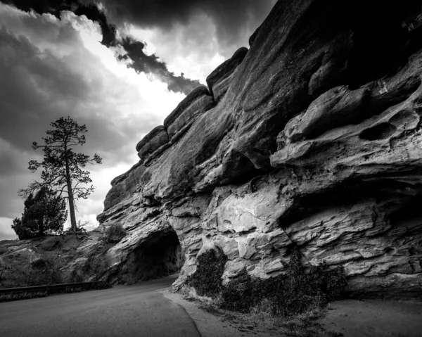Bulutlu gökyüzüne karşı kayaların oluşumlarının gri tonlu görüntüsü.