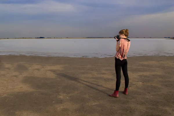 Young Caucasian Woman Taking Picture Frozen Lake Standing Shore — Stockfoto