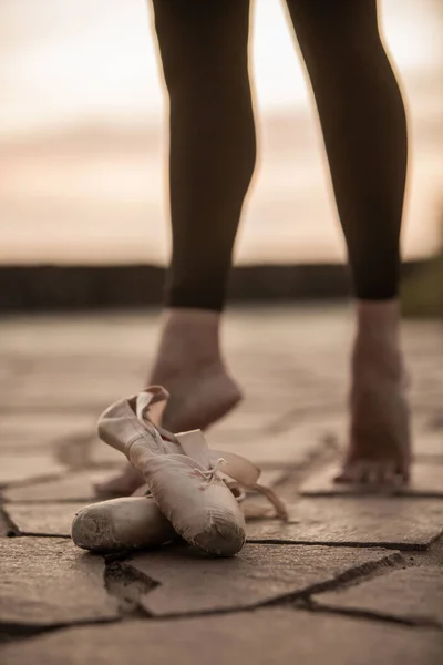 夕阳西下 一个女舞蹈家的脚和尖鞋在前景的垂直的照片 — 图库照片
