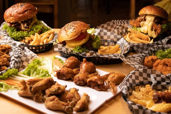 A couple of baskets with crispy chicken burgers, french fries and fried chicken on a table