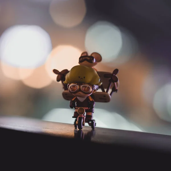 A closeup of a Pop Mart toy figurine of Dimoo preparing to fly isolated on a bokeh background