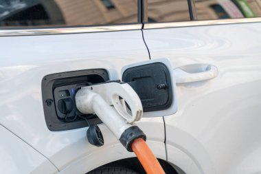 İstasyonda şarj edilen beyaz bir elektrikli arabanın yakın çekimi.