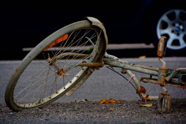 A closeup shot of a damaged and old bicycle on the ground