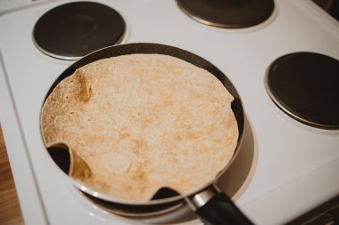 A closeup of a pancake in a black pan on the stove