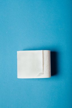 A vertical shot of a toilet paper on a blue background