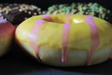 closeup of several colorful donuts on a table, with dark background