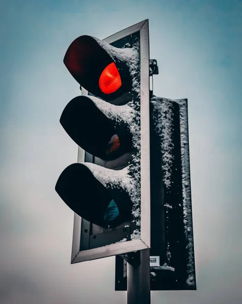 Closeup shot of traffic lights with the red lamp on and covered in snow