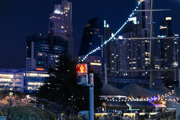 A red pedestrian traffic light and street lights of the city at night