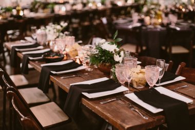 The dining table setting with pink drinking glasses and floral centerpieces