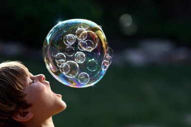 A selective focus shot of a boy playing with bubbles at daytime