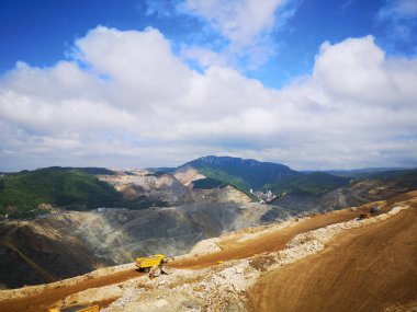 The view of the cars on the mine against the mountains range and blue sky. Majdanpek, Serbia.