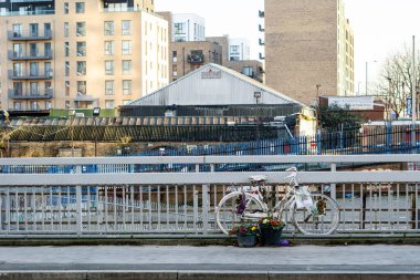 Beyaz bir anıt bisiklet zincirlenmiş ve caddede bir bisiklet yoluna yaslanmış binalar ve açık gökyüzü ile
