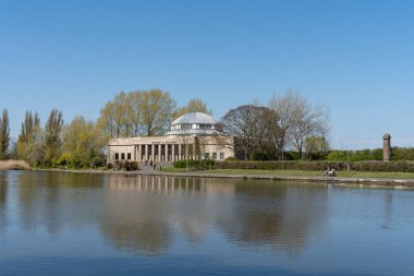 İnsanlar Newcastle 'daki Exhibition Park' ın etrafında Wylam Bira Fabrikası 'nın arka planında Tyne, İngiltere' de dinleniyorlar..