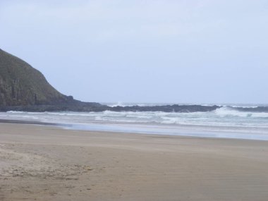 Kasvetli bir günde deniz kıyısındaki uçurumların ve dalgaların manzarası.