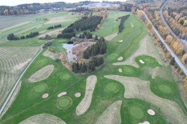 Güzel ormanı olan bir golf sahasının havadan görünüşü.