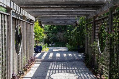 Metal çitlerin arasından geçen taş bir patika. Üzerinde büyük yuvarlak bir tasarım var.