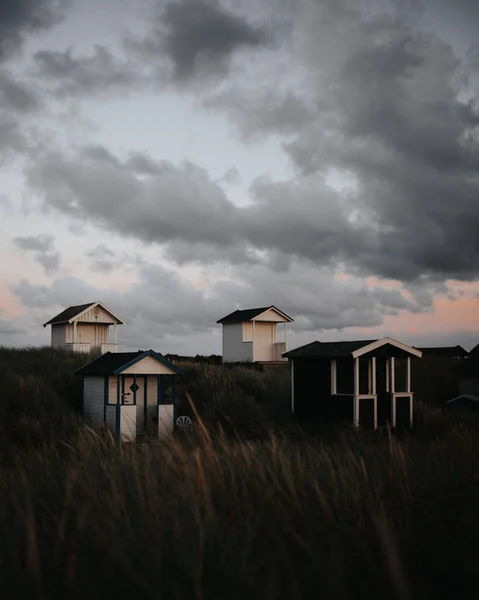 A vertical shot of small colorful cabins in the field during a cloudy day in Skanor, Sweden