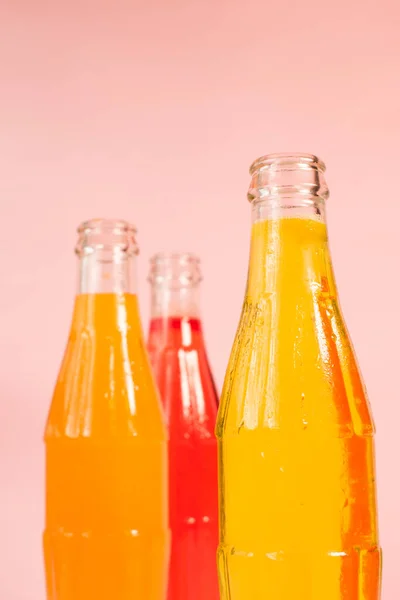 Vertical Shot Glass Bottles Colorful Sparkling Juices Pink Background — Stock Photo, Image