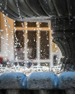 Bir fıskiyenin heykelinin altından süzülen suyun dikey ve yakın çekim görüntüsü.