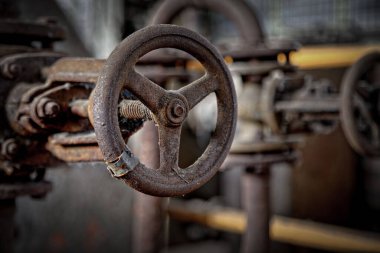 A selective focus shot of an old rusty metallic steering wheel