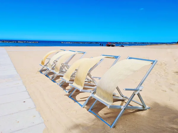 A row of deck chairs blowing in the wind on a beach