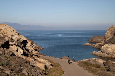 A female walking on a path on the coast of Paratge de Tudela in Cap de Creus Cape in Costa Brava