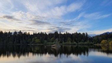 A breathtaking view of the Lost Lagoon, Stanley Park on blue cloudy sky background