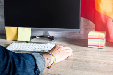 Ofiste çalışan bir adamın LGBT aksesuarlarıyla yakın plan fotoğrafı.