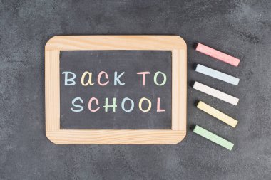 Chalkboard with the text back to school, education concept, colorful chalk pieces