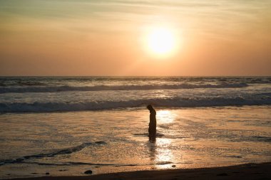 Bir kadın yürüyor ve manzaralı bir günbatımının tadını çıkarıyor.