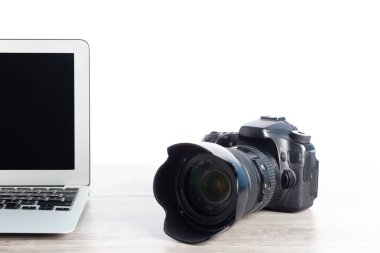 A closeup of a camera and a laptop on a wooden table