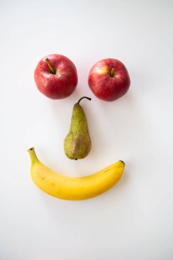 A vertical shot of a happy smiley face made out of fruits