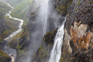 A famous Voringfossen gorge with waterfall and green summer mountains, Norway.